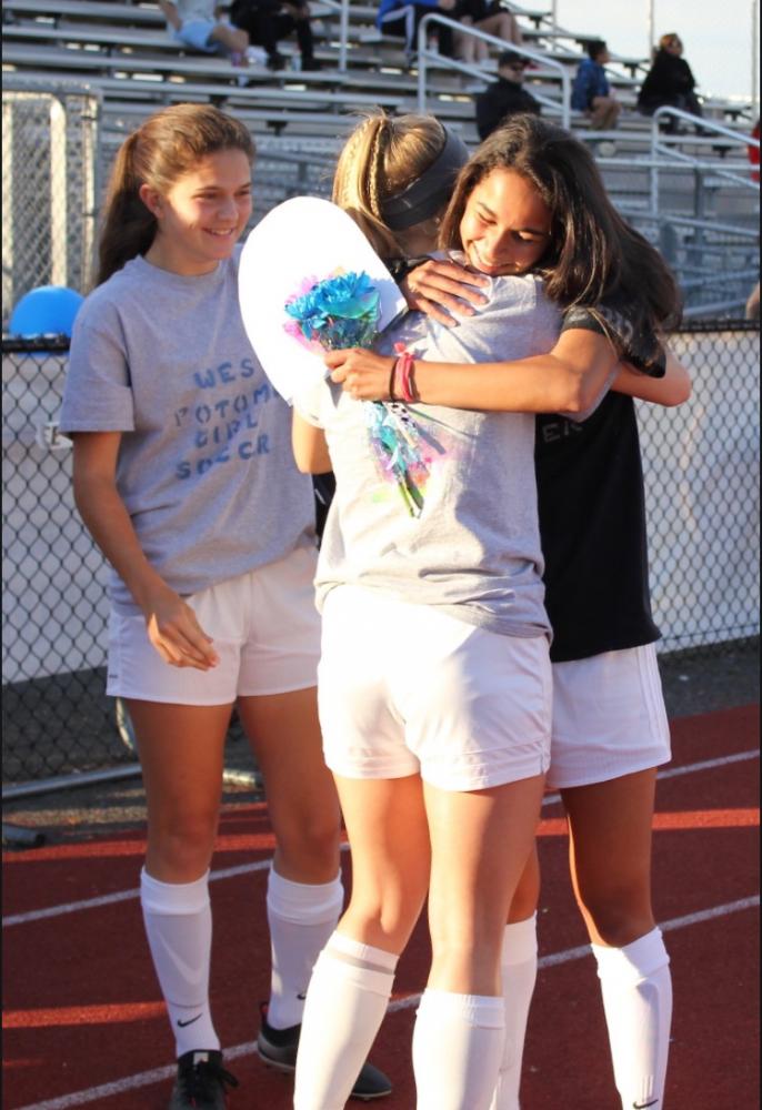 Sophomore Mary Bell (left) and junior Ashlyn Hendrix (middle) giving gifts to senior Catherine Chittal