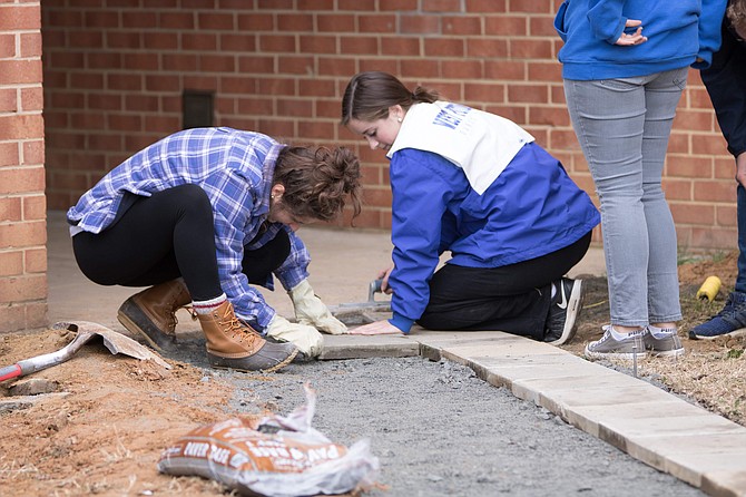 Pictured is sophomore Kylie Rapp (right) laying the stones for the new walkway on the side of Quander building.