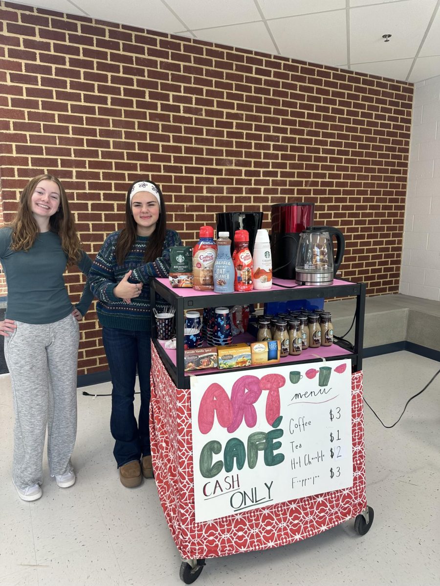Junior Alexis Haymon and Senior Emma Weyrauch volunteer to work the Art Cart Cafe. Hot coffee is brewed fresh, boiling water is available for a selection of herbal teas, Starbucks Frappuccinos, and many creamers are provided to spruce up a beverage.