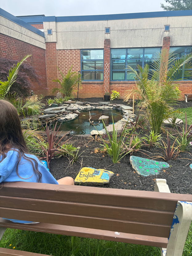 A student enjoys a peaceful moment by the pond.