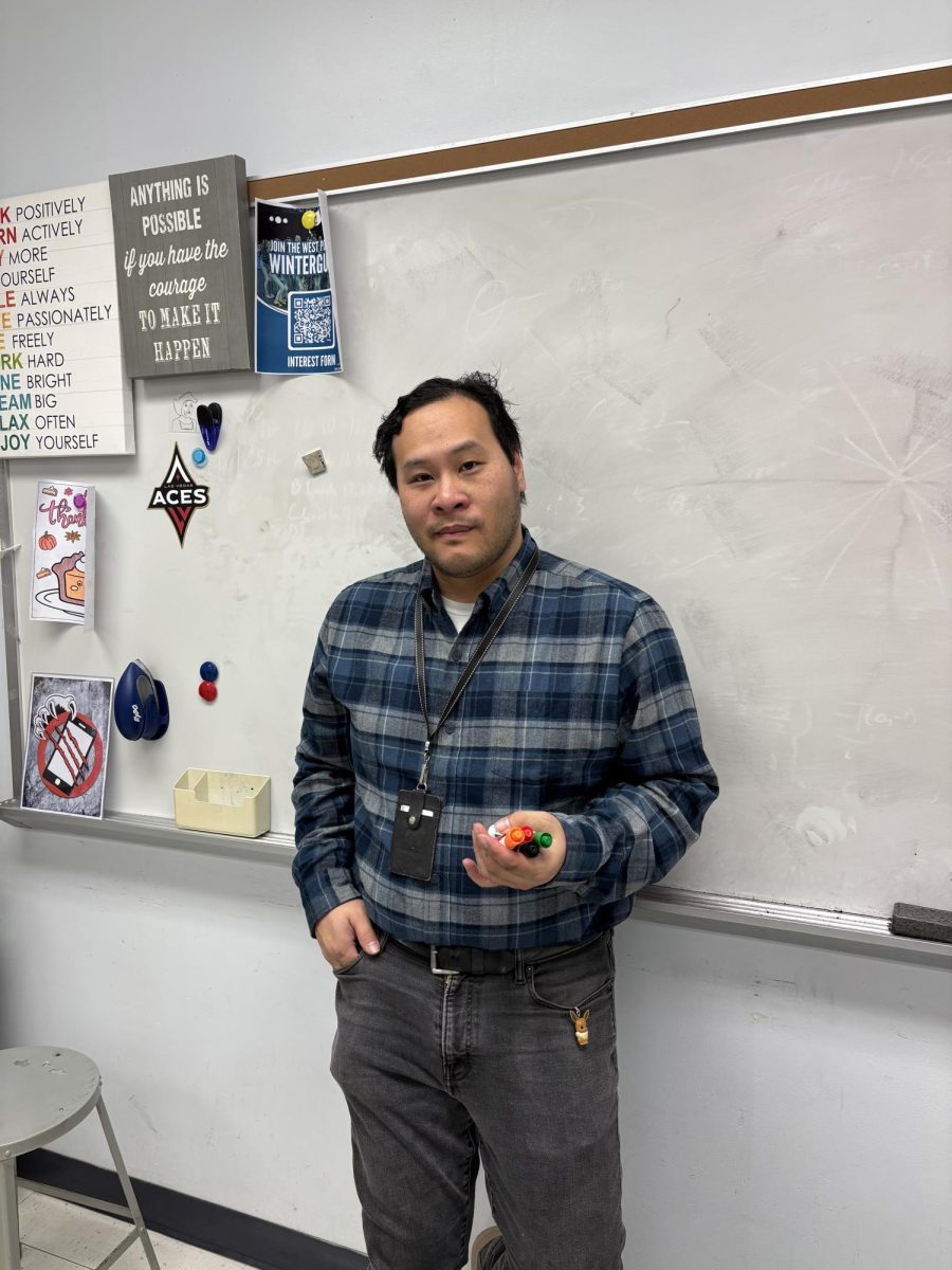 Mr Minh standing in his math class with markers in hand.